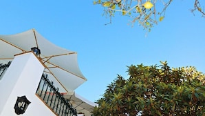 A white building with a large umbrella and a black lantern. - Hostal La Posada de Conil (Conil de la Frontera)