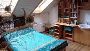 A room with a bed, skylight, bookshelves, a sink, and a small table. - Gästehaus und Cafe - Lichthof (Gaedheim)
