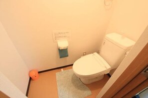 A small bathroom with a toilet, a paper towel dispenser, and a small rug on the floor. - Kyoto Nijo Machiya (Kyoto)