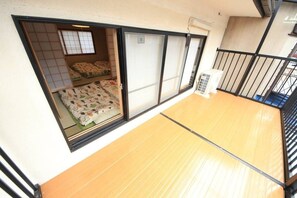 A room with tatami flooring, a sliding shoji door, and a bed with floral bedding. - Kyoto Nijo Machiya (Kyoto)