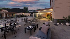 Ein Terrassenbereich im Freien mit Tischen, Stühlen, einer Couch und Topfpflanzen.