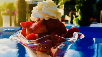 Un postre en un bol de cristal sobre una mesa junto a la piscina.