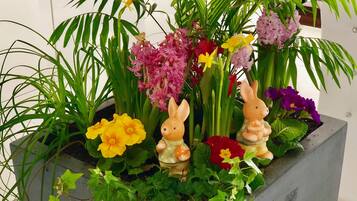 Ein Blumentopf mit verschiedenen Blumen und einer Hasenfigur.