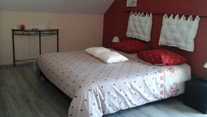 A bedroom with a bed, pillows, a nightstand, and a wall-mounted lamp. - Chambres d’hôtes les alouettes (Vair-sur-Loire)