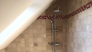 A shower area with tiled walls and floor, a showerhead, and a drain. - Chambres d’hôtes les alouettes (Vair-sur-Loire)