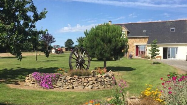 A residential property with a stone pathway, a decorative wheel, and a variety of colorful flowers. - Chambres d’hôtes les alouettes (Vair-sur-Loire)