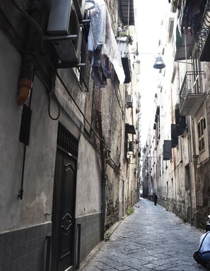 A narrow cobblestone street flanked by buildings with balconies and air conditioning units. - B&B San Lorenzo (Naples)
