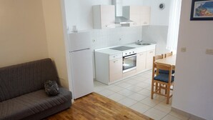 A compact living space with a kitchenette, a sofa, and a dining area.