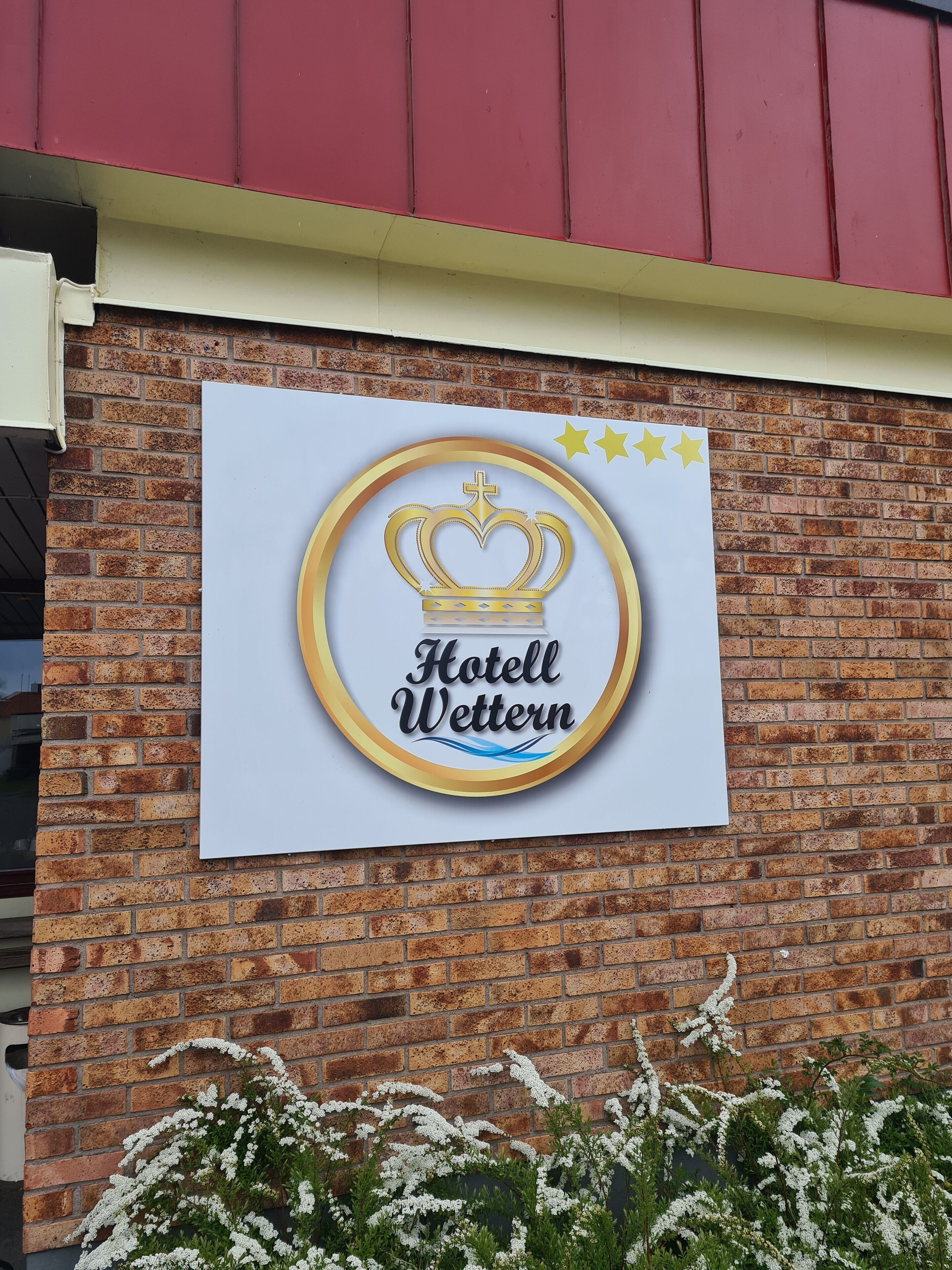 Hotellin kyltti, jossa on kruunulogo ja nimi ”Hotel Wettern”, on kiinnitetty tiiliseinään.