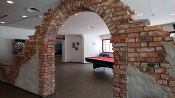 Una habitación con mesa de billar, paredes de ladrillo y un soporte para tacos.