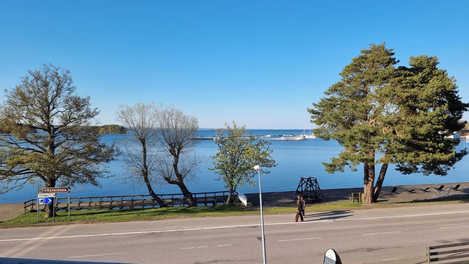 Vista de un lago con un sendero, árboles y un columpio.