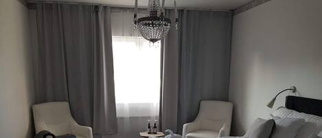 Una habitación de hotel con dos camas, una araña, una mesita con botellas y una silla.