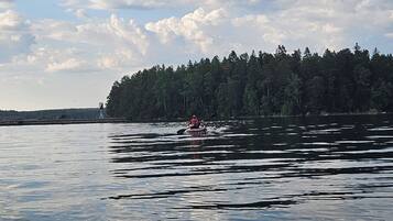 A calm lake with a kayak in the foreground and a forested island in the background.