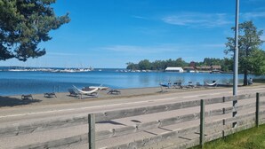 A waterfront promenade with a wooden walkway, benches, and hammocks. - Hotell Wettern (Karlsborg)