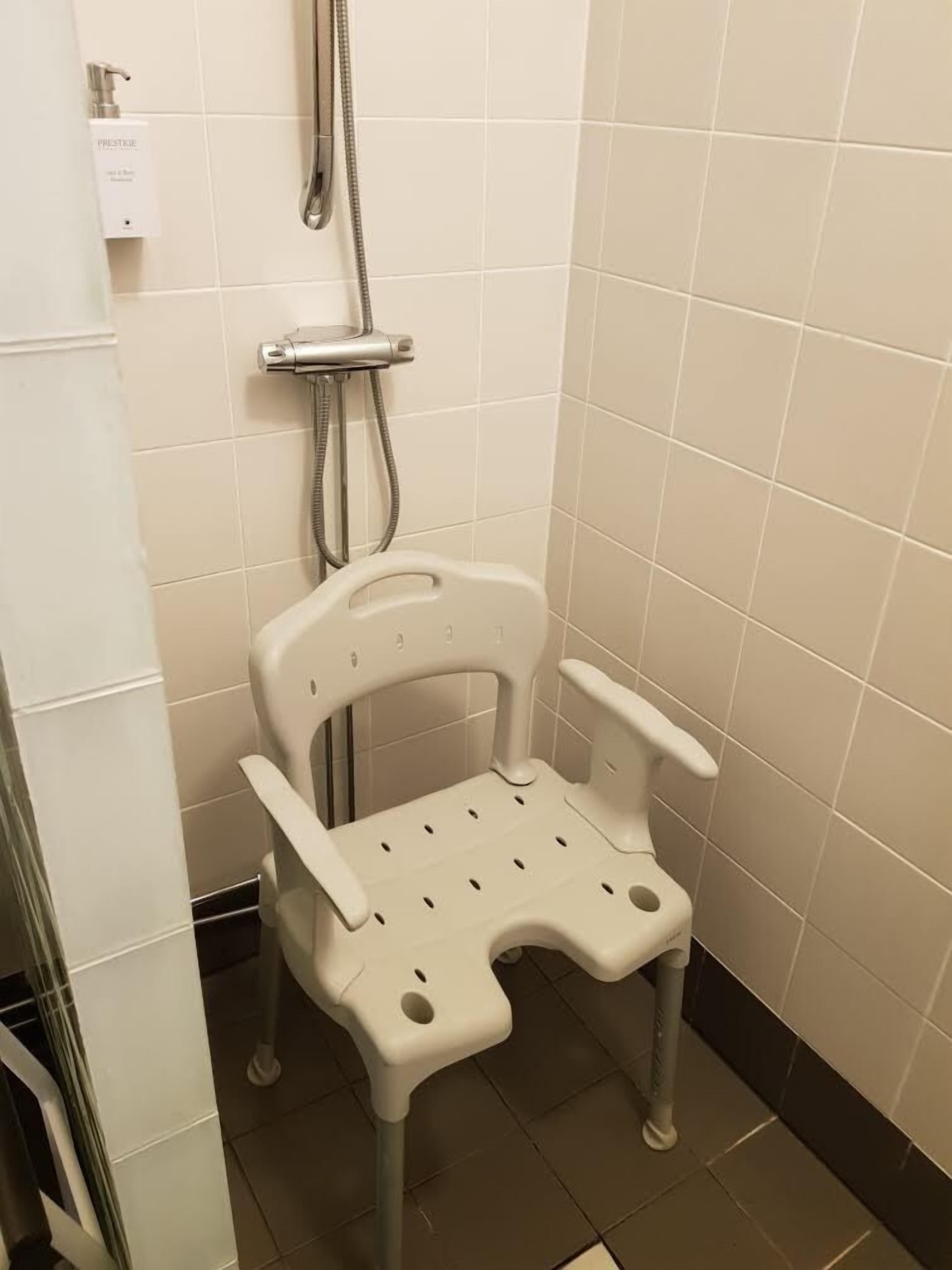 Ein Badezimmer mit Dusche, Toilette und einem Handtrockner.