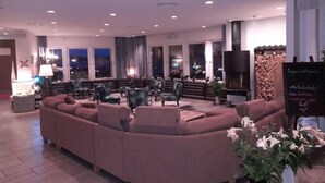A modern lounge area with a large sectional sofa, multiple armchairs, and a fireplace. - Hotell Wettern (Karlsborg)