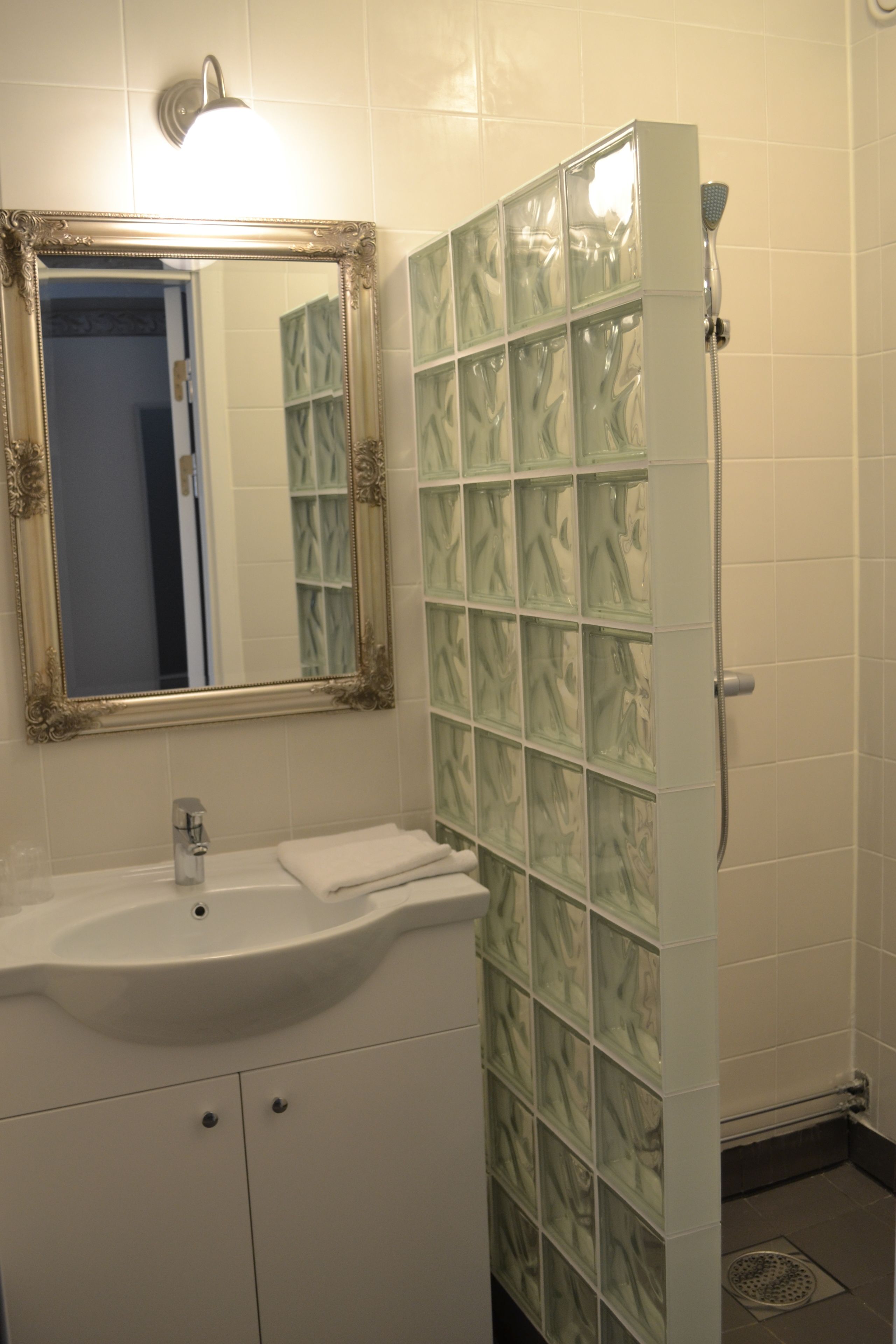 A bathroom with a white sink, a mirror with an ornate frame, and a shower with a glass door.