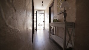Un pasillo con un banco de madera, una mesa con lámpara y una puerta que da a un espacio exterior.