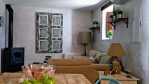 Una sala acogedora con una mesa de madera, un sofá y un tazón de vidrio con manzanas verdes.