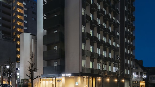 A multi-story hotel with a prominent R&B sign, a modern architectural design, and a well-lit entrance.