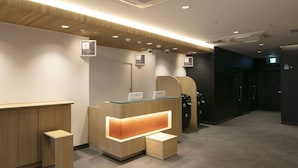 A modern reception desk with a glass top, wooden accents, and numbered signs for rooms.