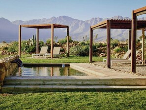 Una piscina al aire libre, sombrillas, sillones reclinables de piscina