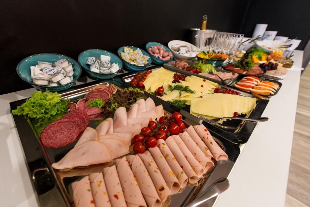 A buffet table with various food items including meats, cheeses, and vegetables.