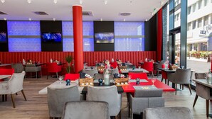 A restaurant with red and grey chairs, tables with menus, and a large red pillar.