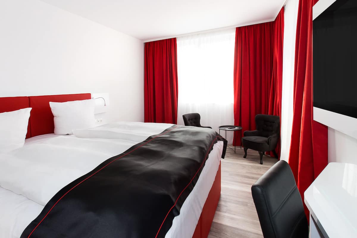 Una habitación de hotel con una cama grande, un escritorio, una silla y una mesita.