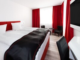 Una habitación de hotel con una cama grande, un escritorio, una silla y una mesita.