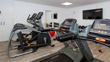 Une salle de sport équipée de tapis de course, de vélos elliptiques et d’une variété d’appareils de musculation.