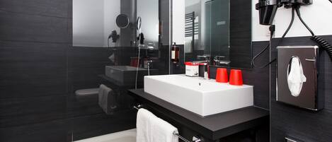 Une salle de bain moderne avec un grand miroir, un lavabo blanc et un meuble-lavabo noir.