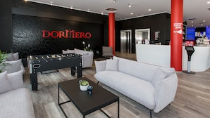 A modern lobby with a foosball table, sofas, and a reception desk.