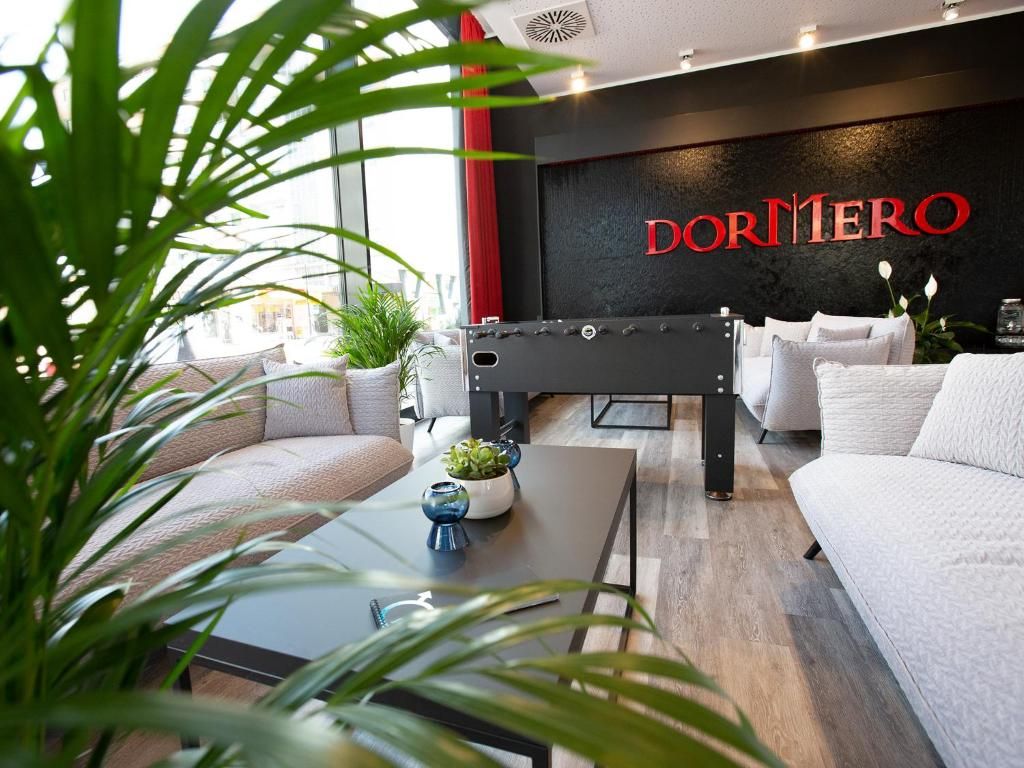 Eine moderne Hotelhalle mit einer Rezeption, Sofas und einem großen Fenster.
