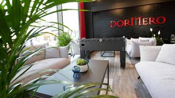 En moderne hotellobby med reception, sofaer og et stort vindue.