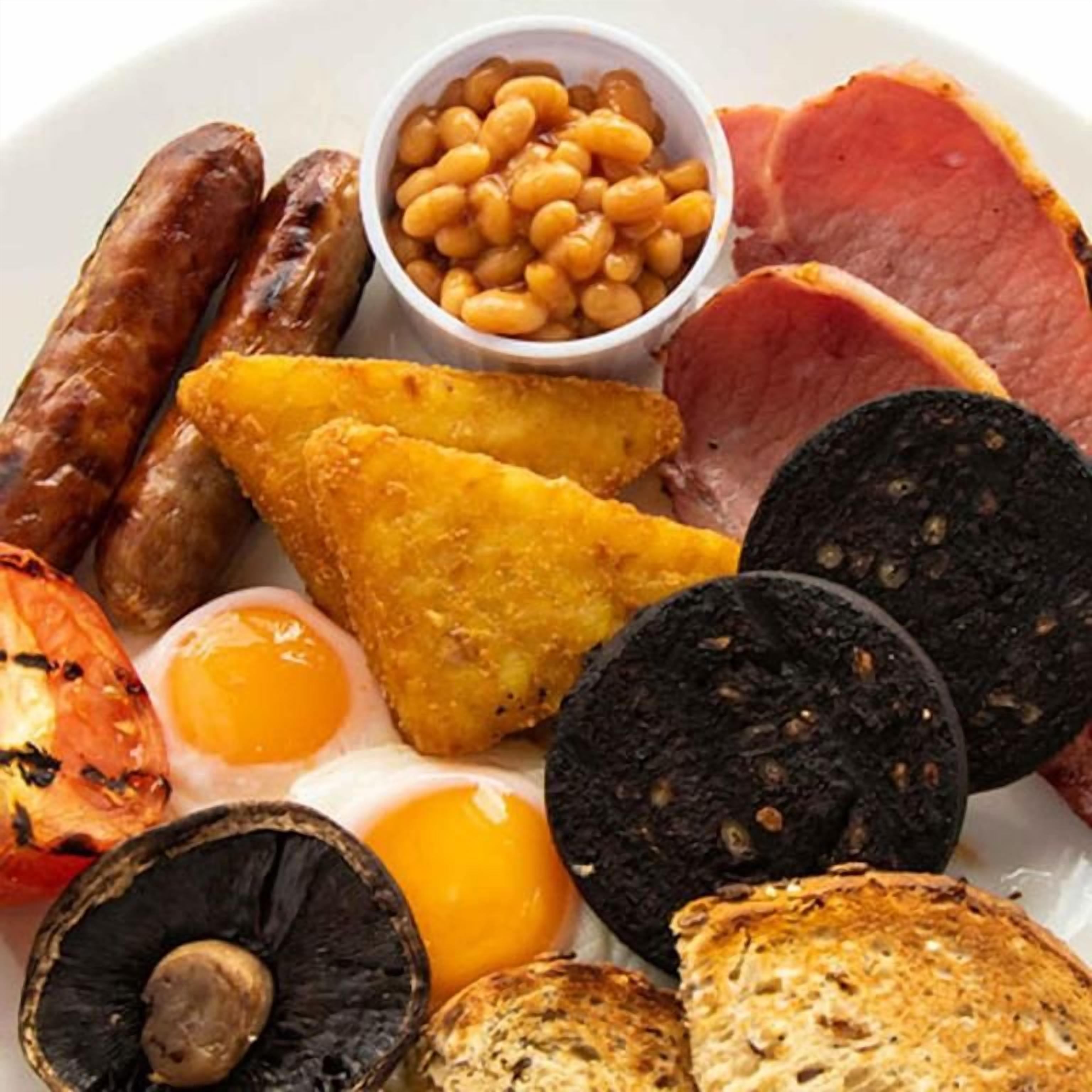 A plate with various breakfast items including sausages, beans, ham, eggs, toast, and black pudding.