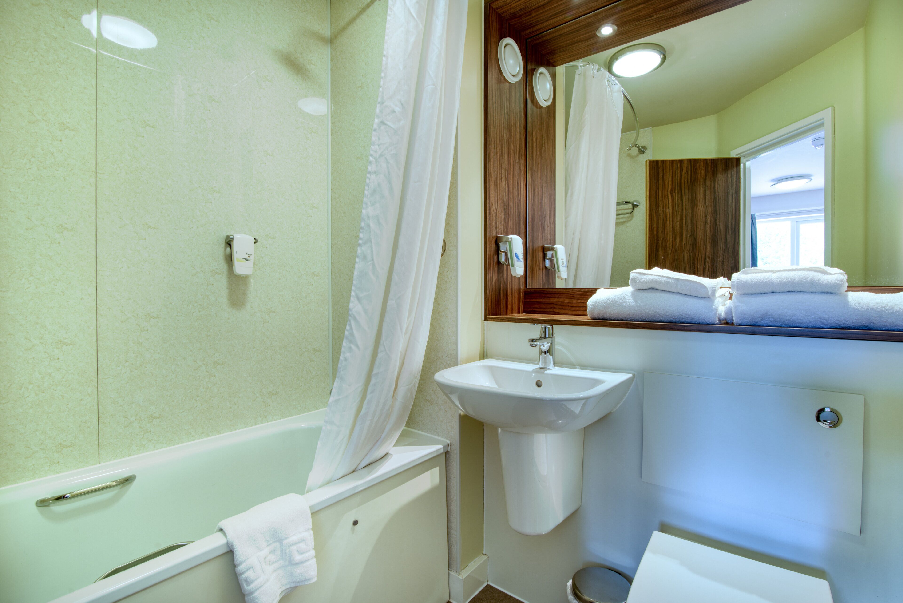 A bathroom with a bathtub, a sink, and a mirror.