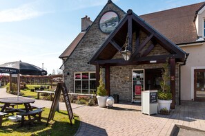 A stone building with a triangular roof, a signboard, and a picnic table.