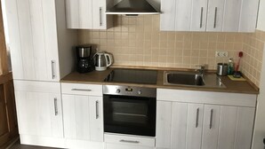 A kitchen with white cabinets, a stainless steel sink, a coffee maker, and a toaster. - Tuxie Haus (Tux)