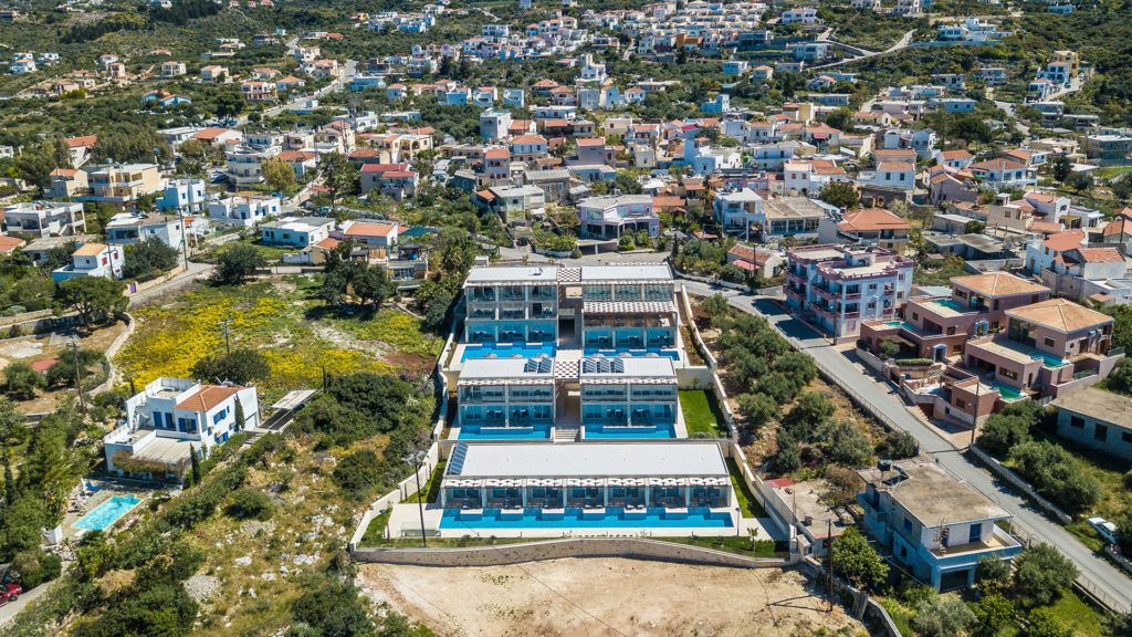 An aerial view of a residential area with a prominent multi-story building featuring a swimming pool.