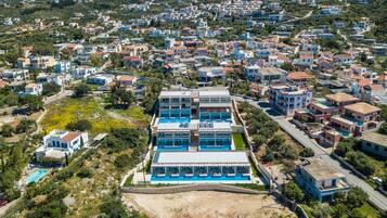 An aerial view of a residential area with a prominent multi-story building featuring a swimming pool.