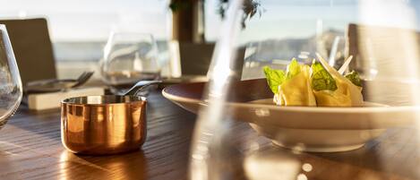 A dining table with a copper bowl, a plate with food, and wine glasses.