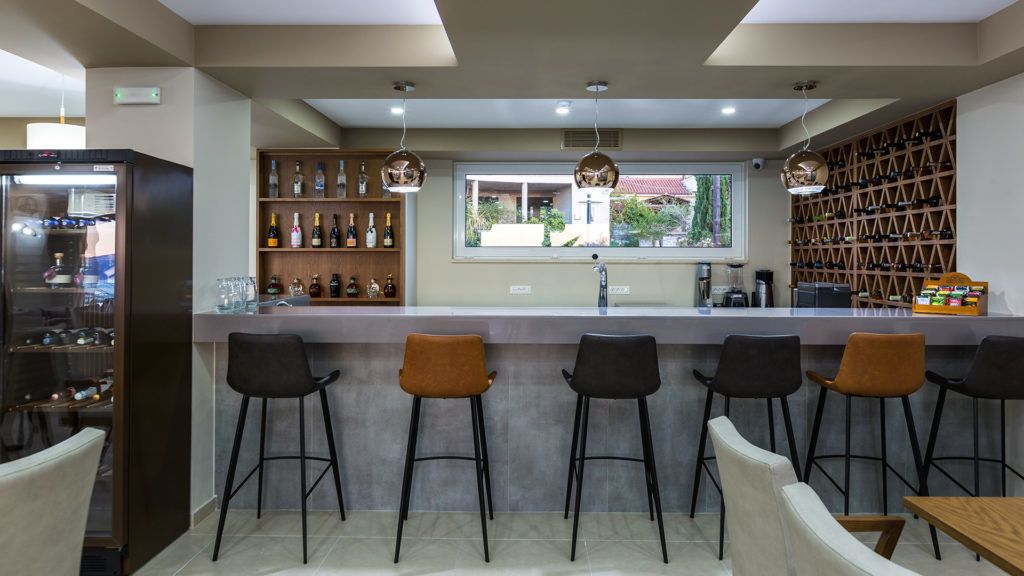 A bar area with stools, a counter, and shelves with bottles.