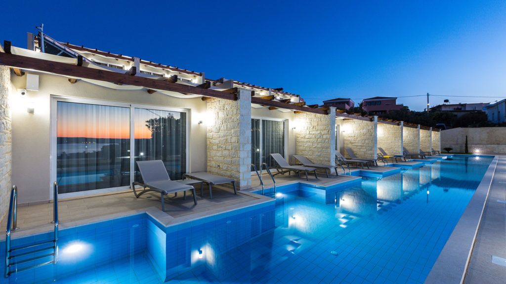 A swimming pool with lounge chairs and a stone facade.