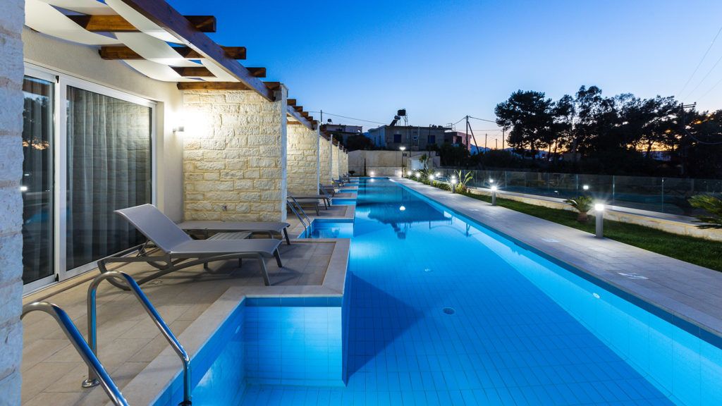 Piscina con sillas de descanso y pared de piedra.