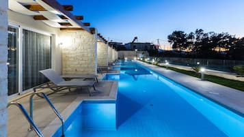Piscina con sillas de descanso y pared de piedra.