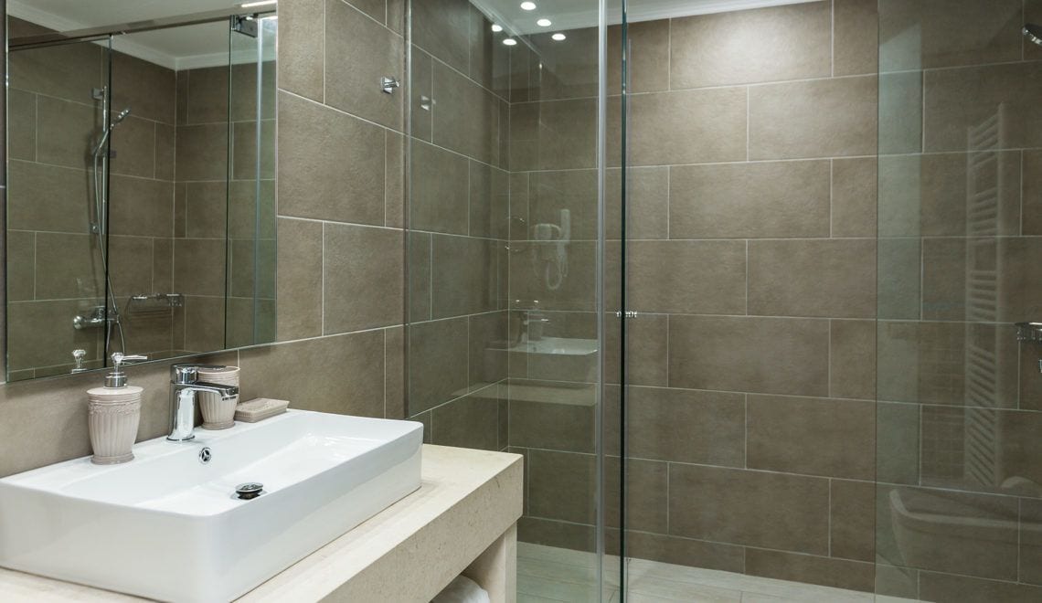 A modern bathroom with a glass-enclosed shower, a white sink, and a large mirror.