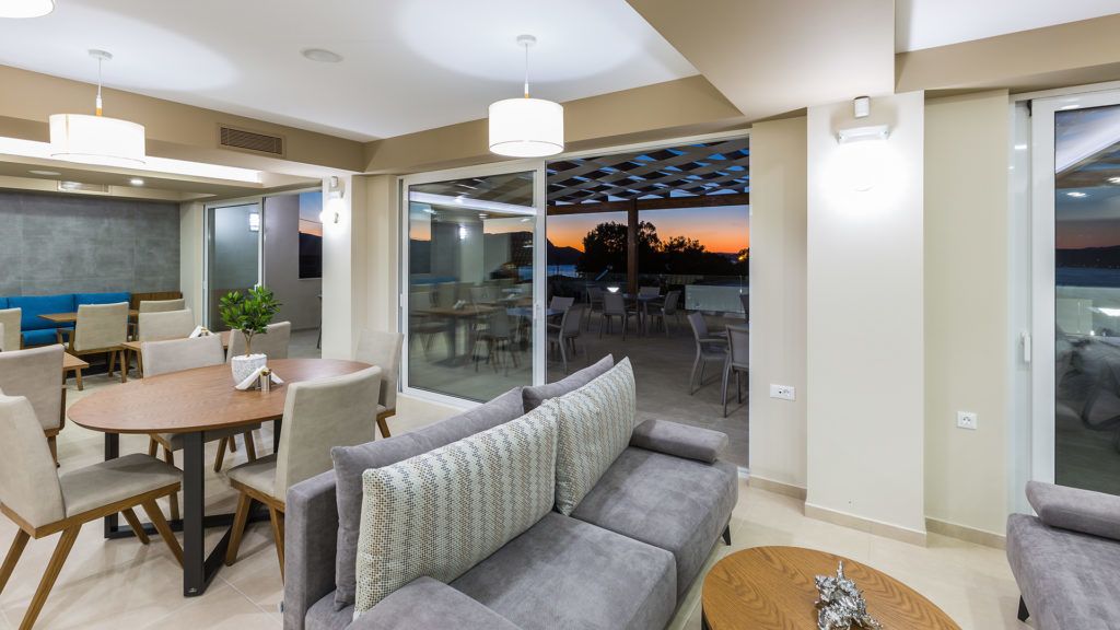 Een moderne woonkamer met een bank, eettafel en stoelen. Er is een schuifdeur naar een terras.