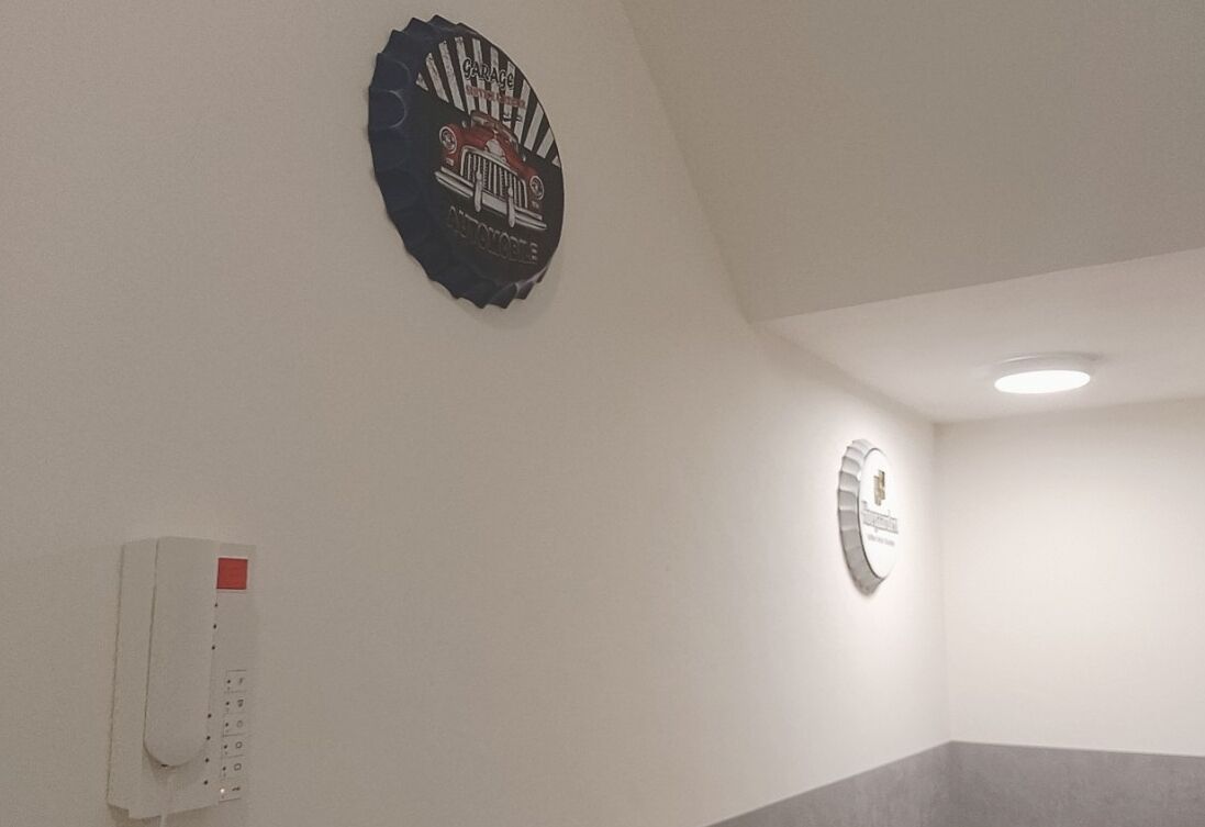 Ein Zimmer mit weißer Wand, einem roten und schwarzen Logo, einem weißen Telefon und einem grauen Teppich.