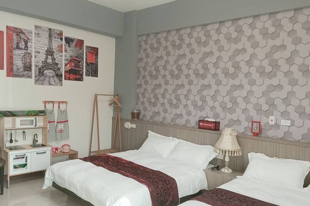 Une chambre d’hôtel avec deux lits, une kitchenette, un miroir et un mur orné de motifs hexagonaux.